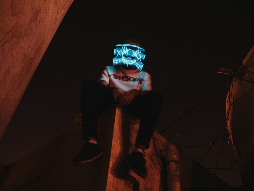 man in blue jacket and black pants sitting on brown concrete stairs