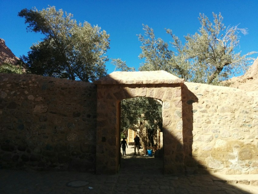 a stone wall with a doorway and people walking through it