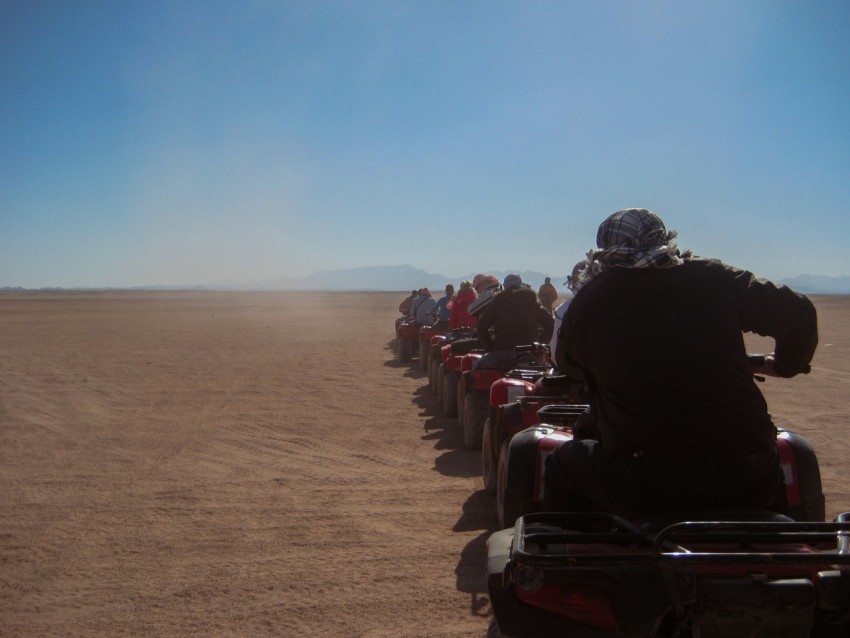 a group of people driving tractors on a dirt road 3L2