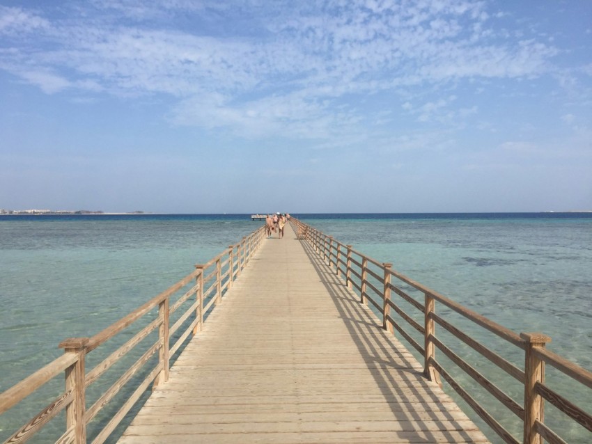 a long wooden pier stretches out into the ocean WJWz45LCA