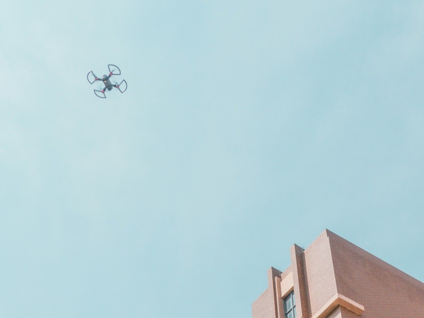 white quadcopter drone fly near brown concrete building myfIfQ