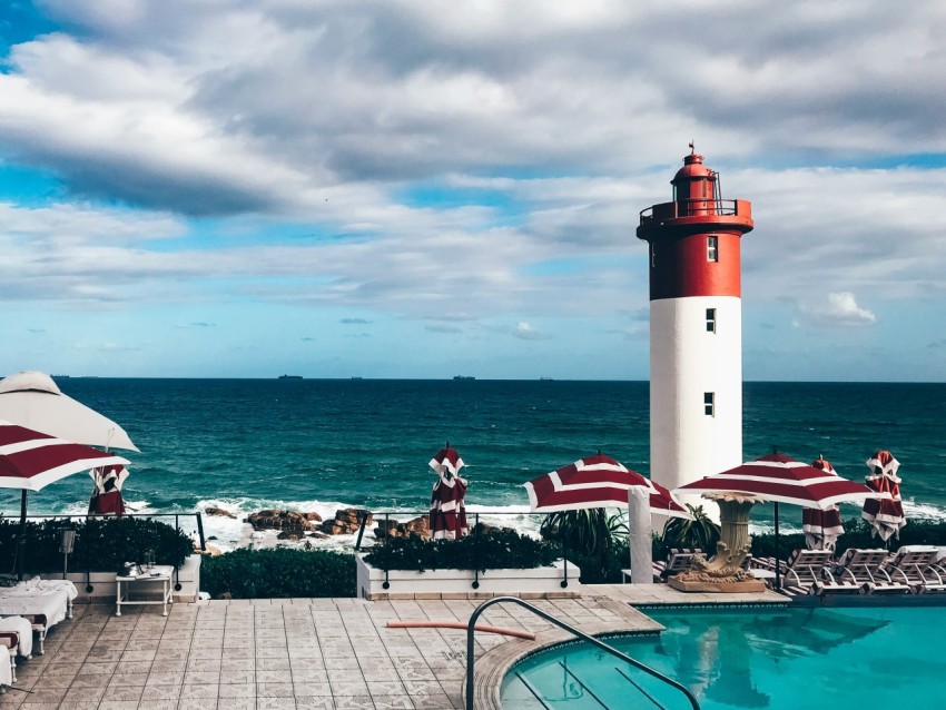 red and white lighthouse near body of water during daytime