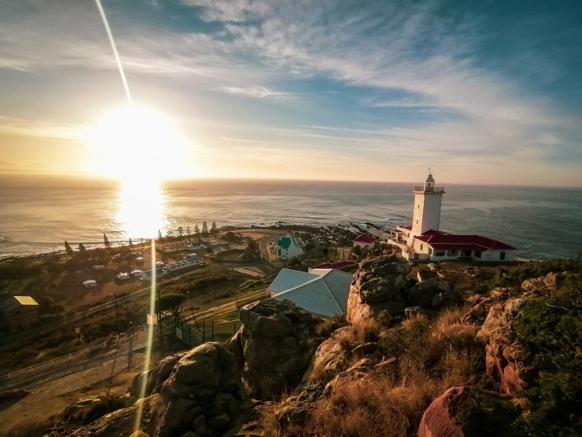 a lighthouse on top of a hill near the ocean