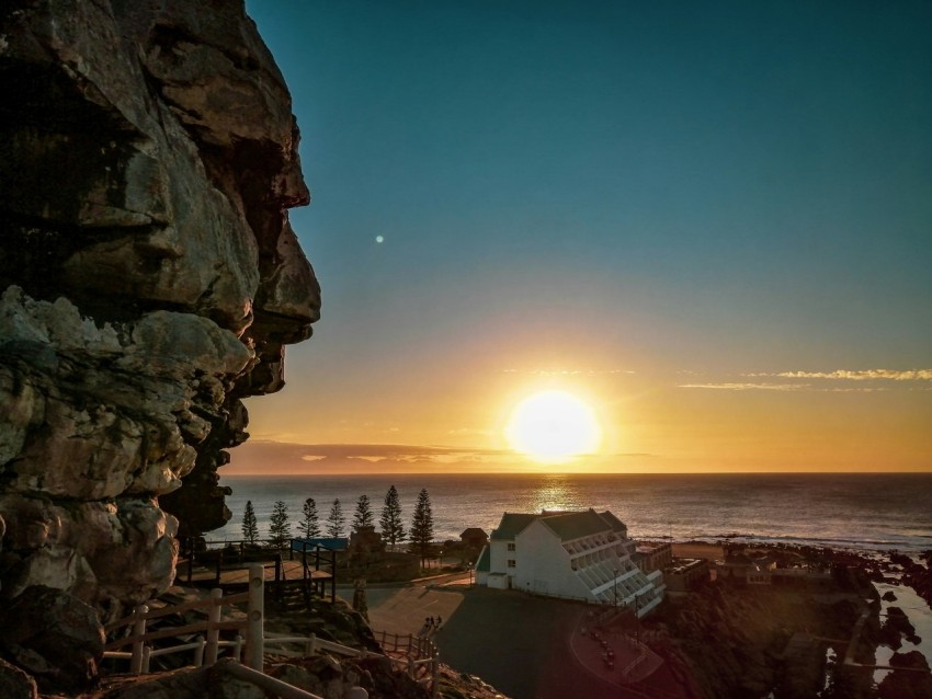 the sun is setting over a rocky cliff by the ocean khw