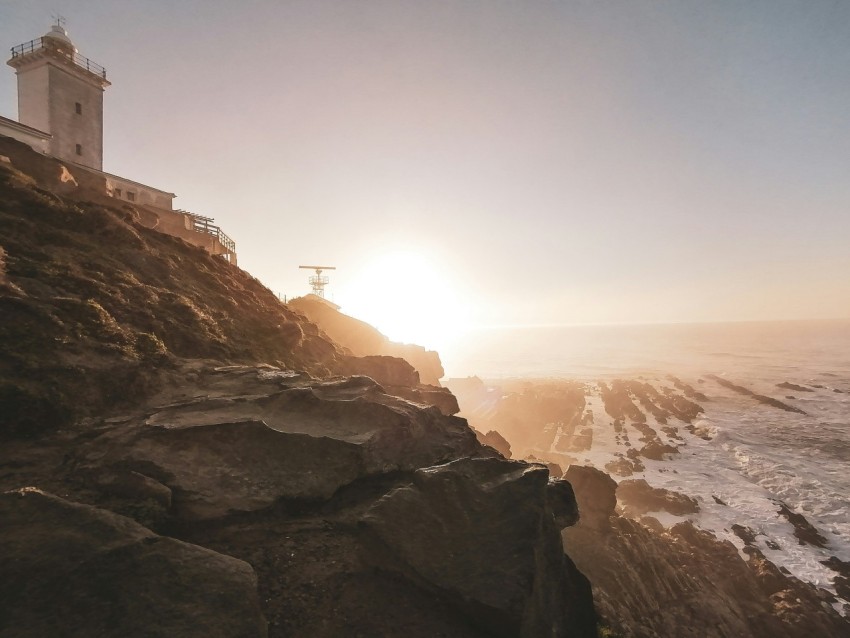 a lighthouse on a cliff overlooking the ocean