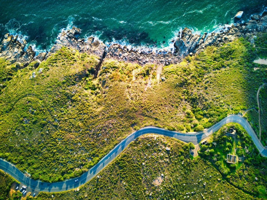 an aerial view of a winding road next to the ocean