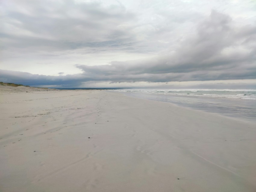 a sandy beach with a few footprints in the sand TUdKAt