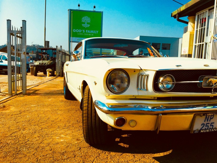 white ford mustang parked near building zR