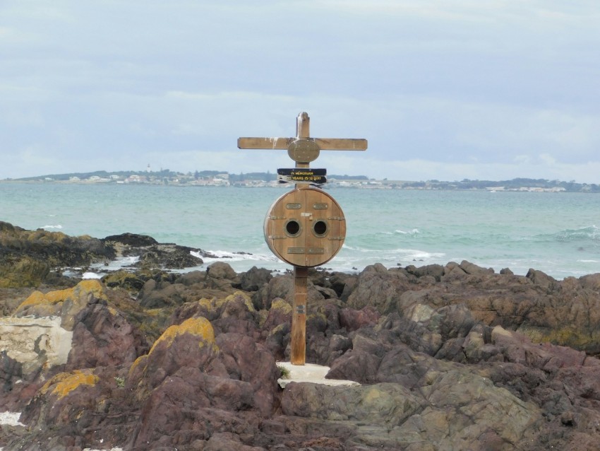 a wooden sign sitting on top of a rocky beach