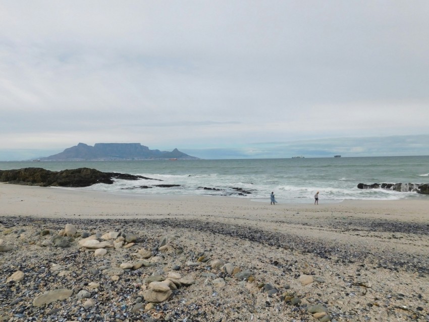 a couple of people standing on top of a sandy beach