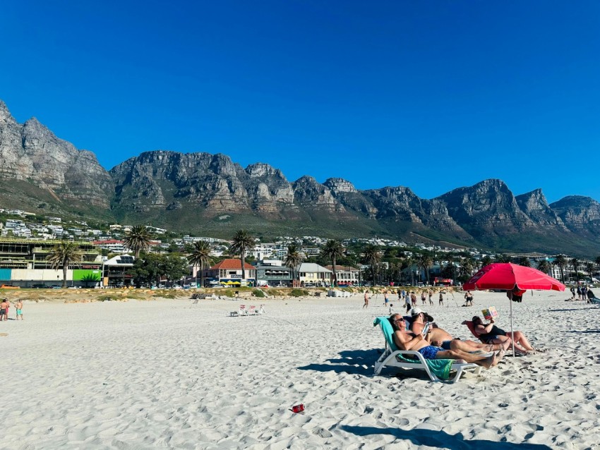 a group of people sitting on top of a sandy beach F AV_h1rT