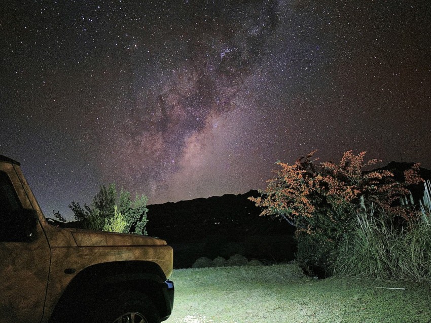 a truck parked in a field under a night sky filled with stars bRD