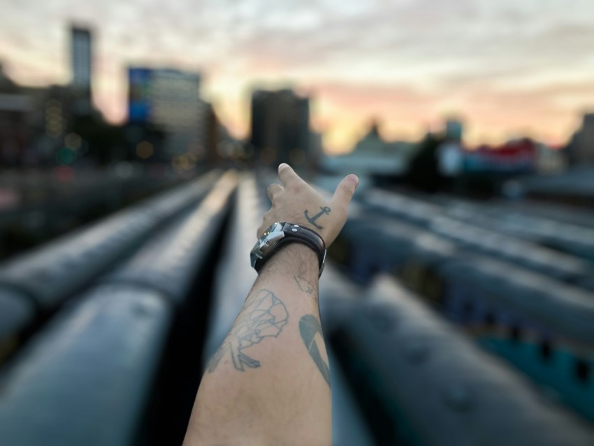 tilt shift photography of mans left hand pointing high rise building