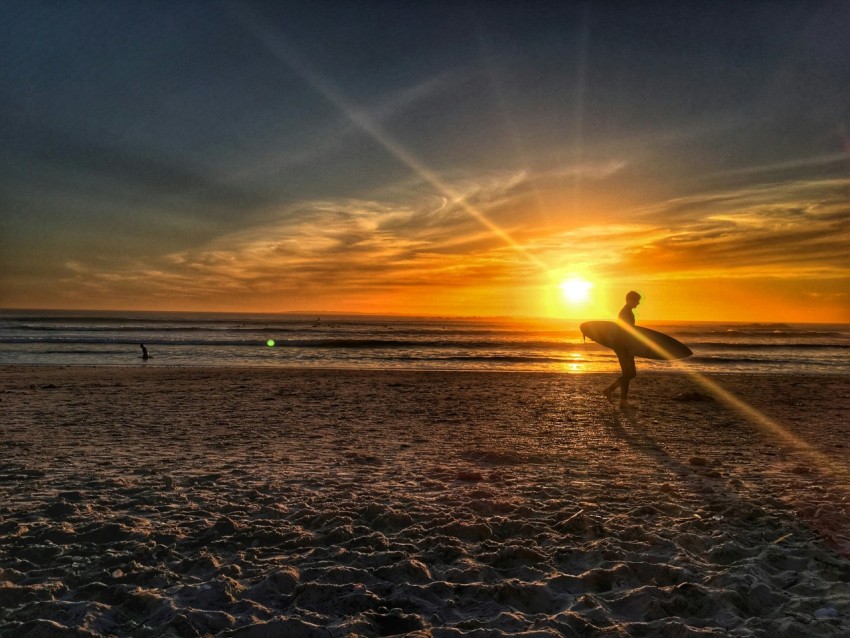 silhouette of person walking on shore during golden hour