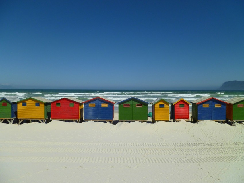 a row of colorful beach huts sitting on top of a sandy beach