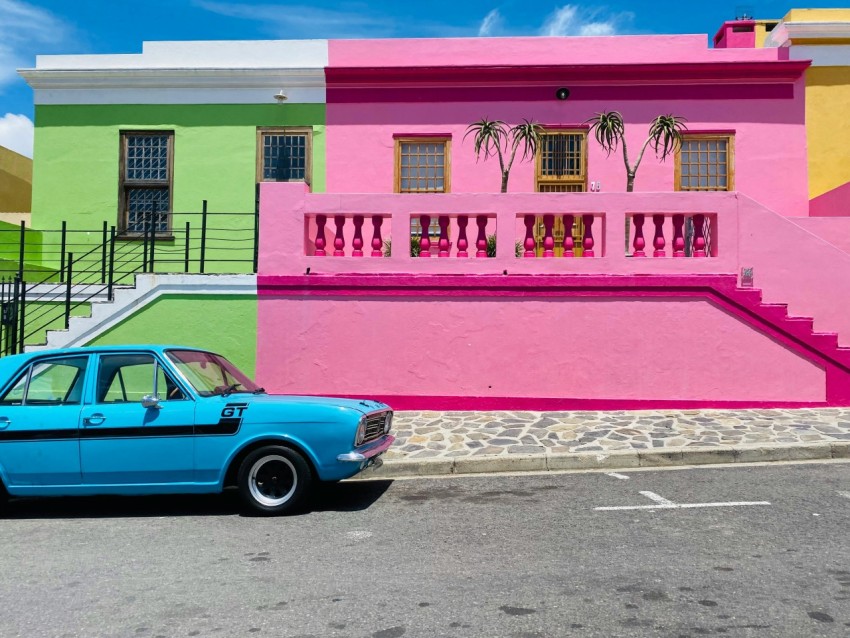 a blue car parked in front of a multi colored building