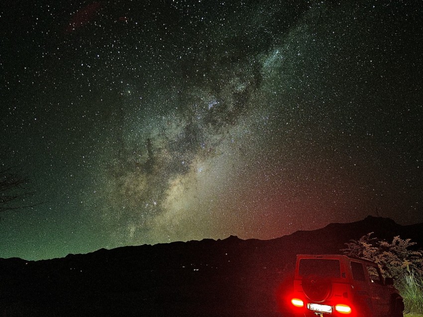 a car is parked on the side of the road under the stars J