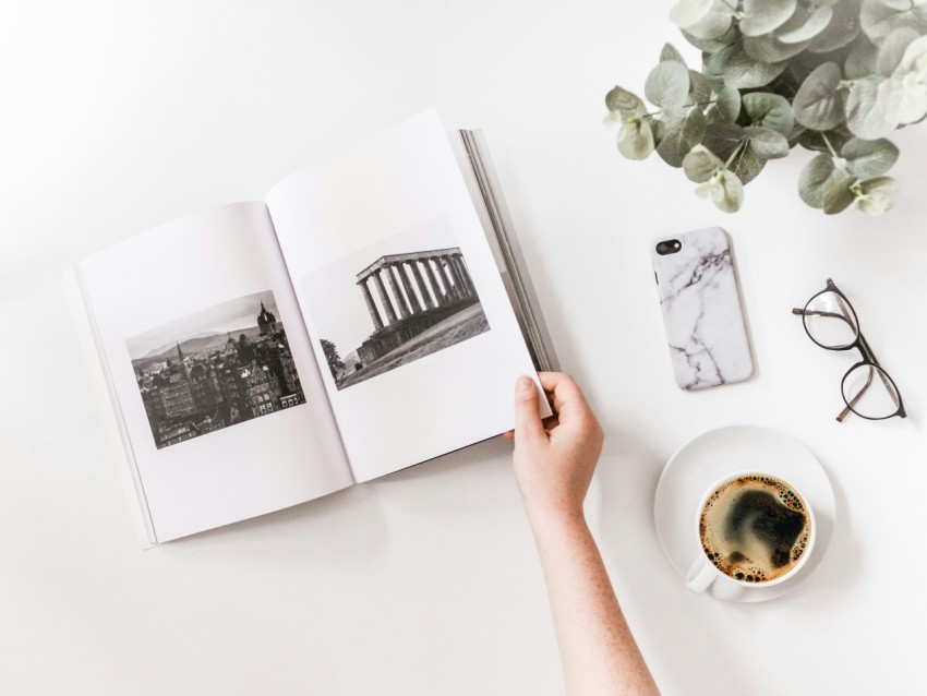 person holding opened book beside iphone