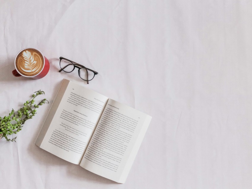 book page beside eyeglasses and coffee _