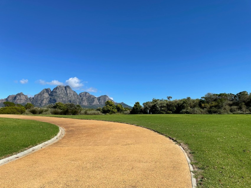 green grass field near mountain under blue sky during daytime