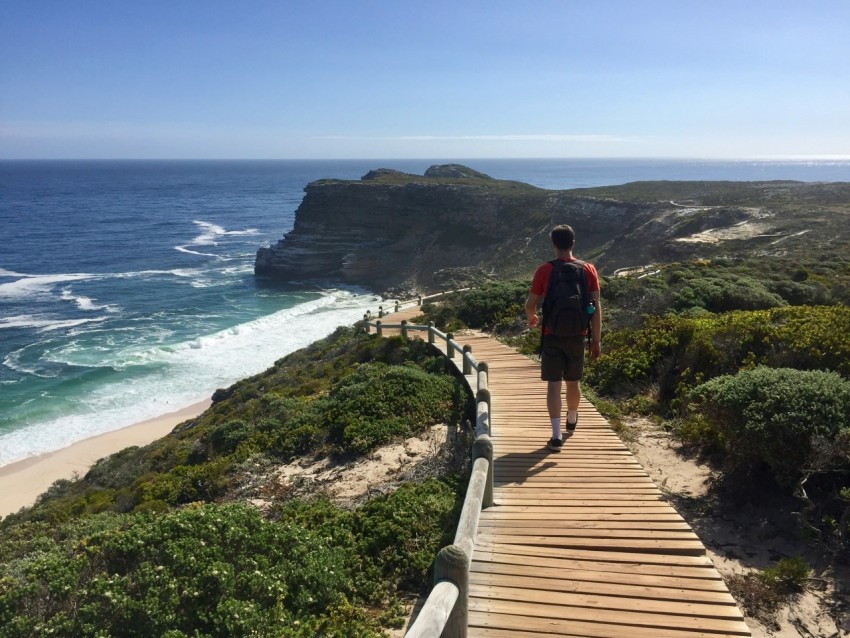 a man walking up a wooden walkway next to the ocean