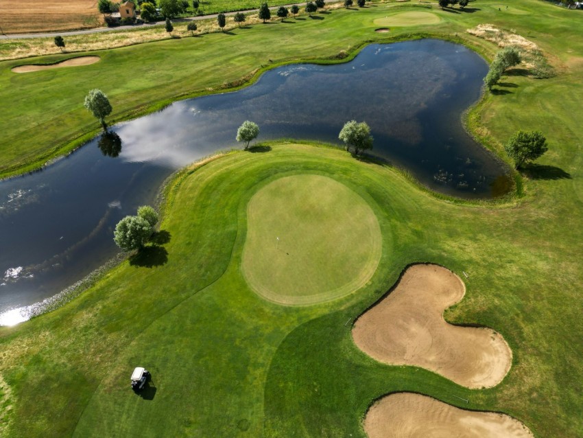 an aerial view of a golf course with a pond