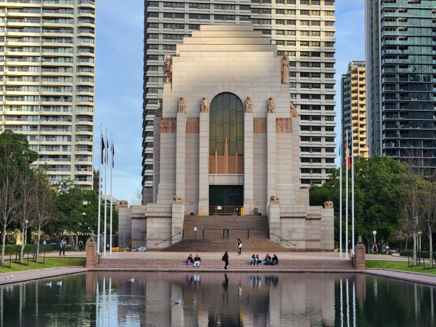 a monument in the middle of a lake surrounded by tall buildings