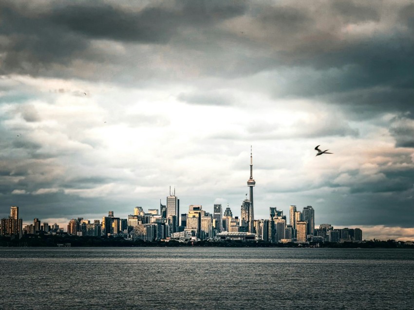 a plane flying over a large city under a cloudy sky