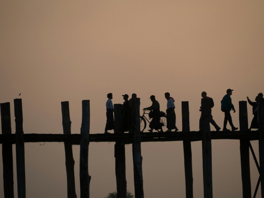 a group of people walking across a wooden bridge