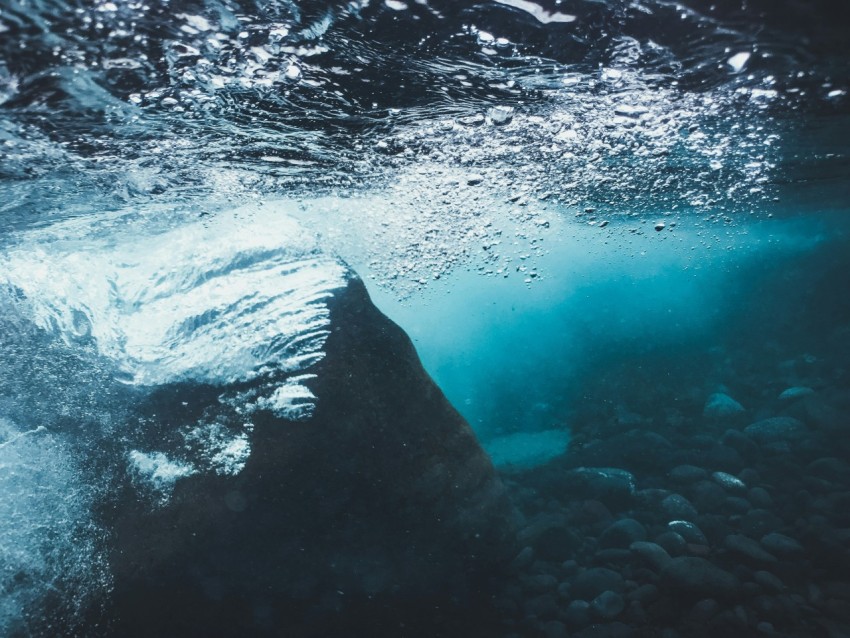 an underwater view of a rock in the water