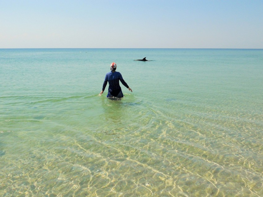 a man in a wet suit wading in the ocean