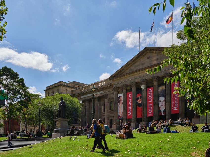 a group of people sitting on the grass in front of a building DCGd