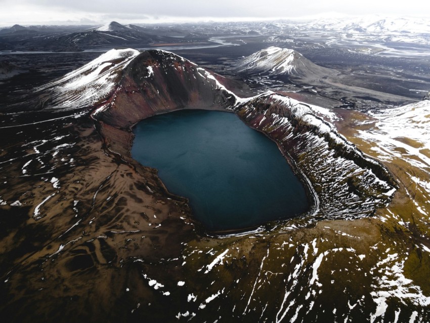 a large blue lake surrounded by snow covered mountains