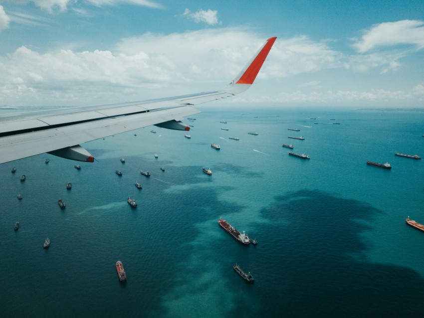 white and red airplane wing over the sea during daytime