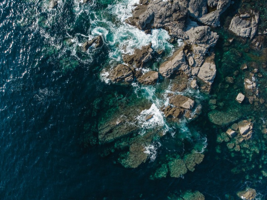 an aerial view of the ocean and rocks