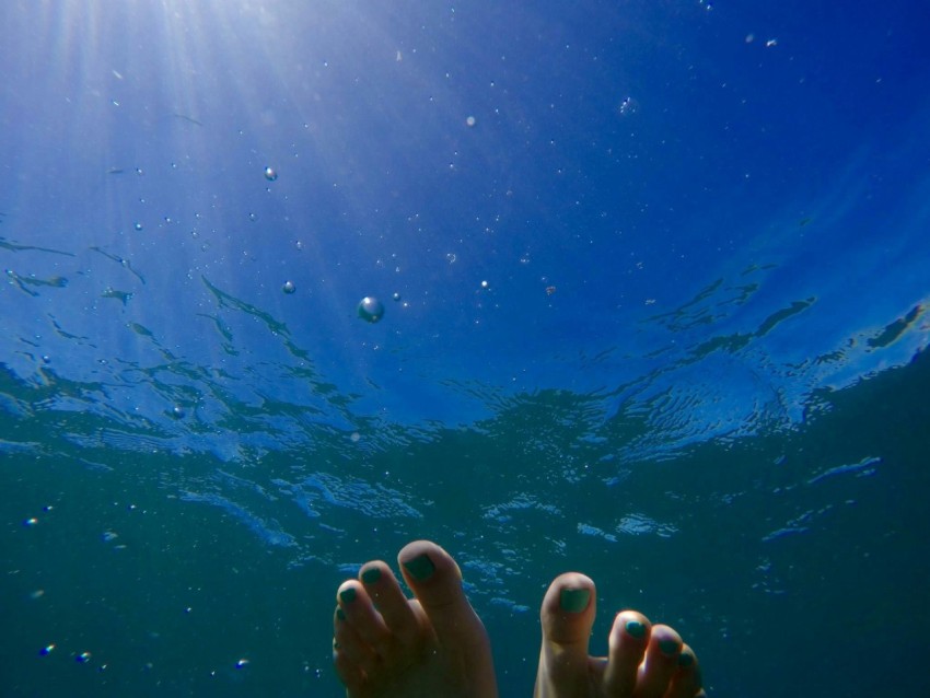 human feet on body of water during daytime