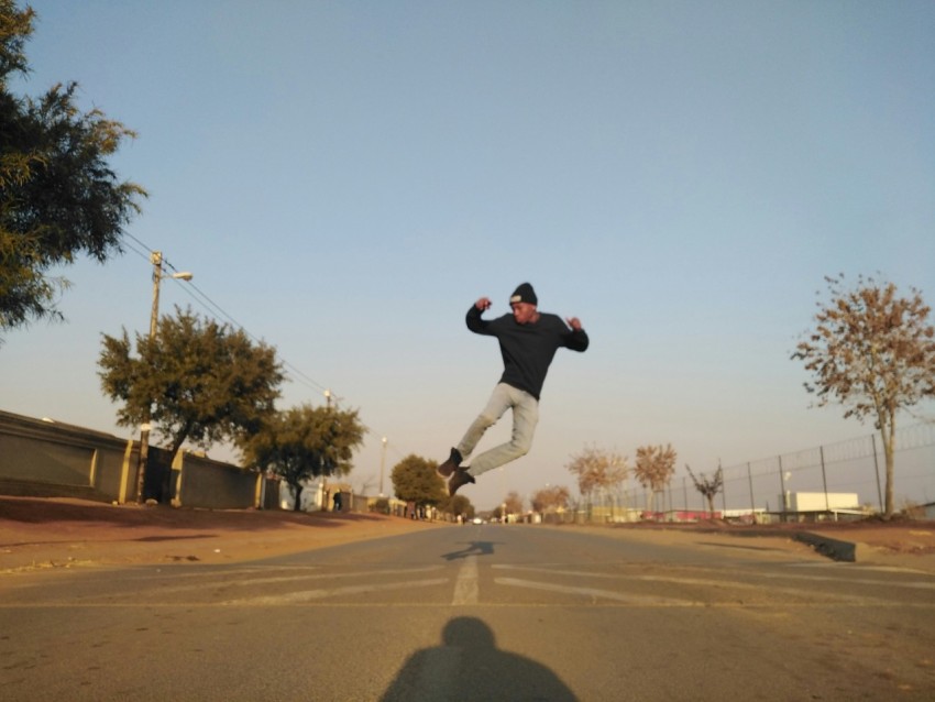 man in black t shirt and black pants jumping on brown field during daytime