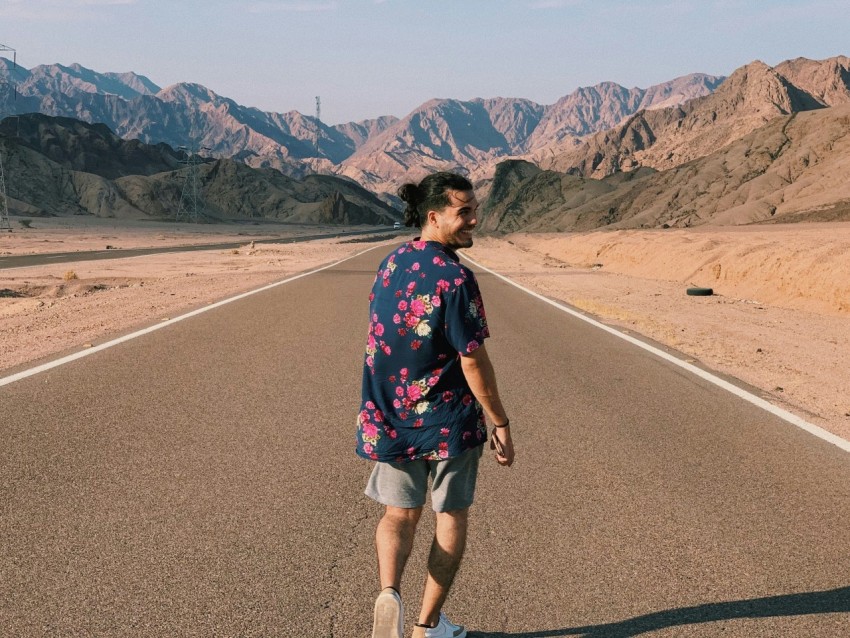 woman in black and pink floral shirt standing on gray asphalt road during daytime