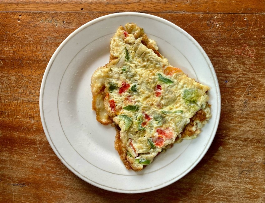 a slice of quiche on a white plate on a wooden table