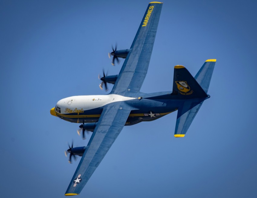 a blue and white plane flying in the sky