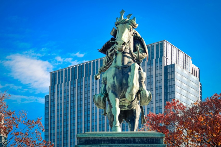 a statue of a man riding a horse in front of a tall building