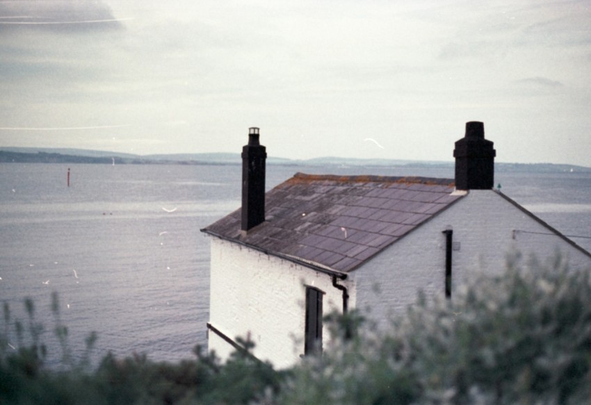 a white house sitting on top of a hill next to the ocean