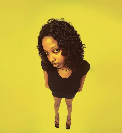 a woman in a black top is standing in front of a yellow background