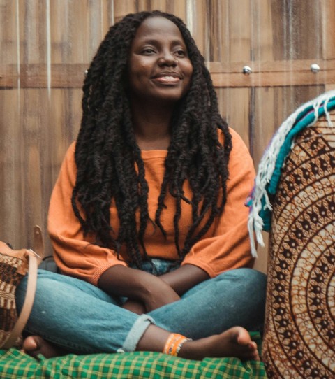 a woman sitting on a bed in front of a wooden wall