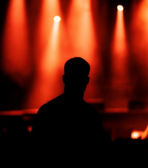 silhouette of man standing in front of stage lights Xlok3KFZ