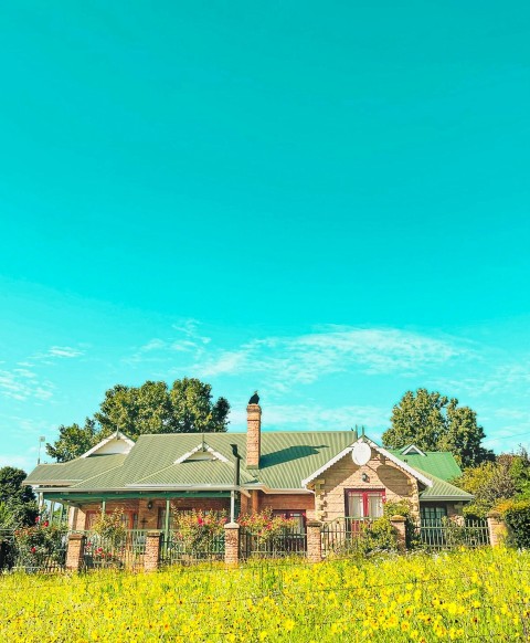 a house in the middle of a green field K0