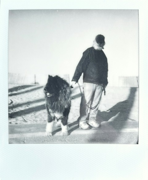 a black and white photo of a man walking a dog