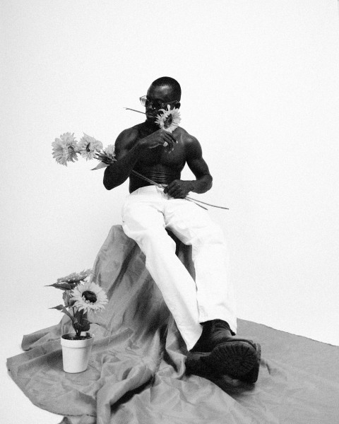 a man sitting on top of a sheet holding flowers