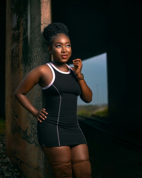 a woman in a black dress leaning against a wall