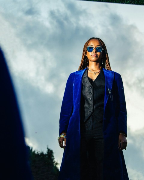 a woman in a blue coat and sunglasses